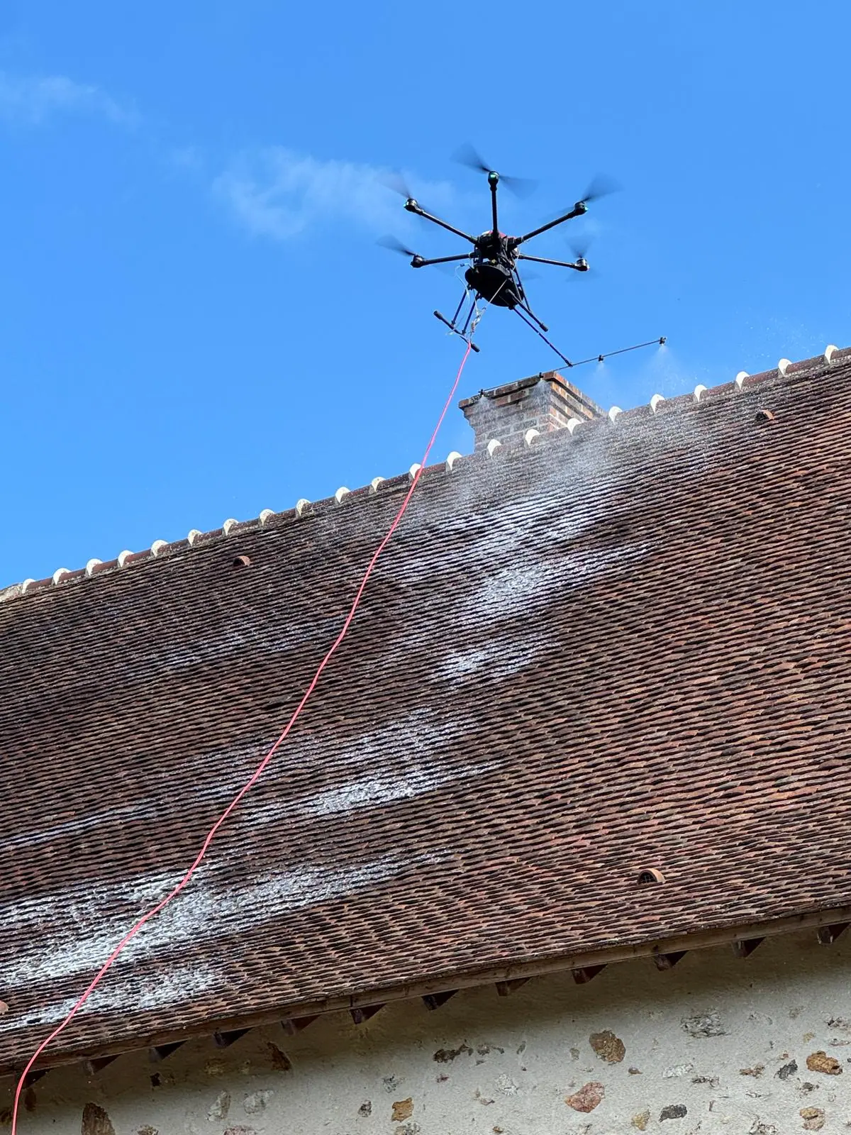 Drone pulvérisant un traitement sur une toiture en tuiles