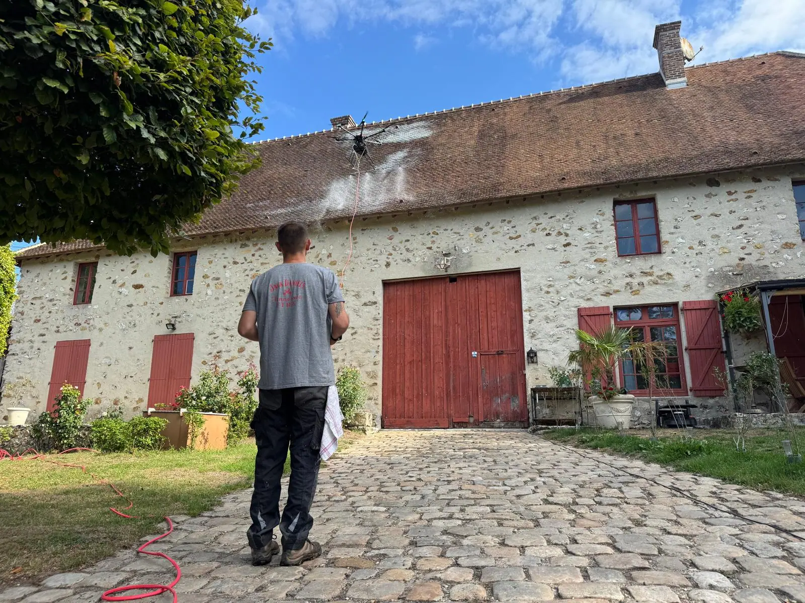 Opérateur pilotant un drone de traitement devant un bâtiment en pierre
